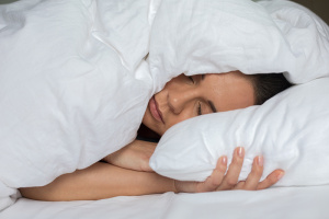 Woman sleeping in bed under blanket